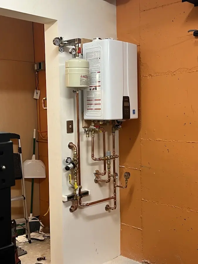 Plumbing technician inspecting water heater connections in St. Marys